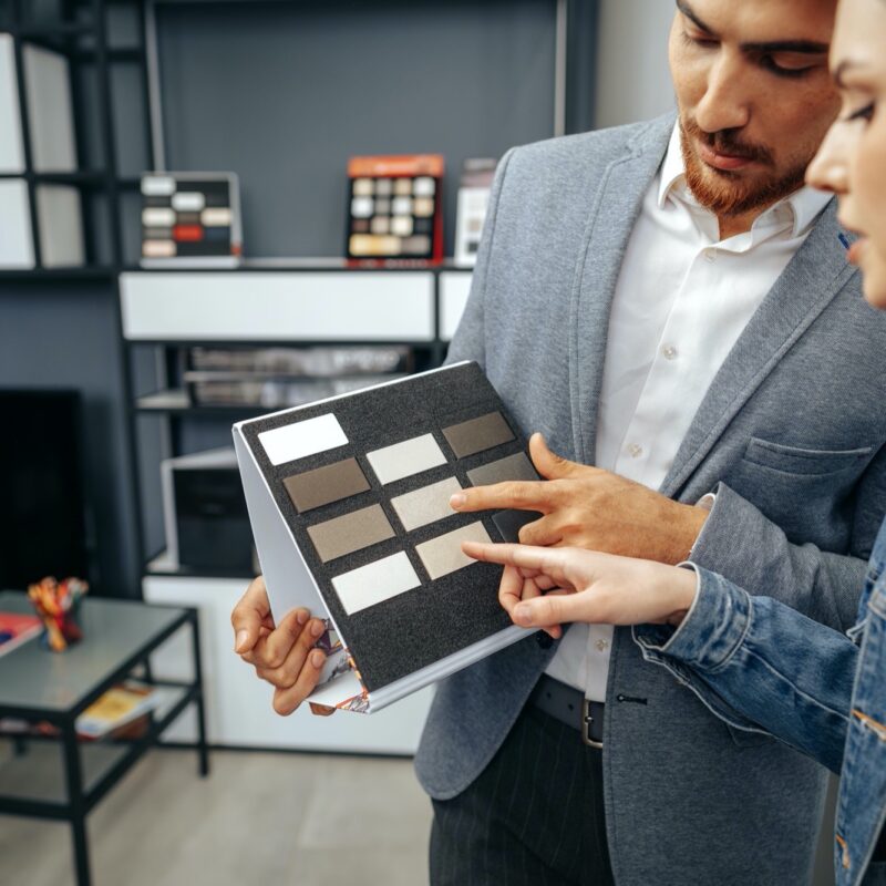 Salesman shows color swatches to lady customer for new kitchen furniture close up