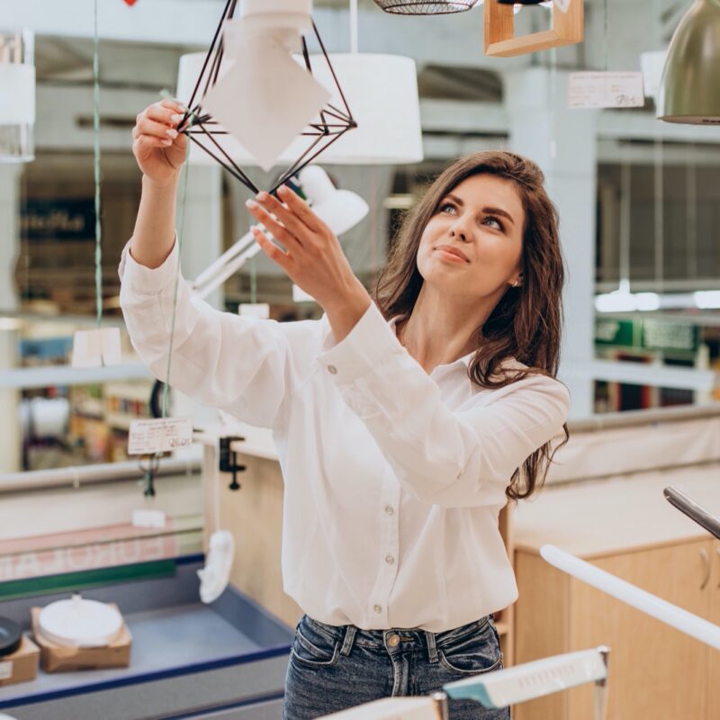 Young woman choosing chandelier in building center Young woman choosing chandelier in building center